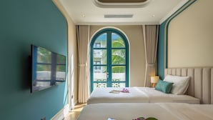 Une chambre d’hôtel avec deux lits, une télévision et une grande fenêtre avec des rideaux.
