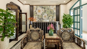Un intérieur de style traditionnel, agrémenté de meubles richement décorés, d’un mur orné et de plantes en pot.