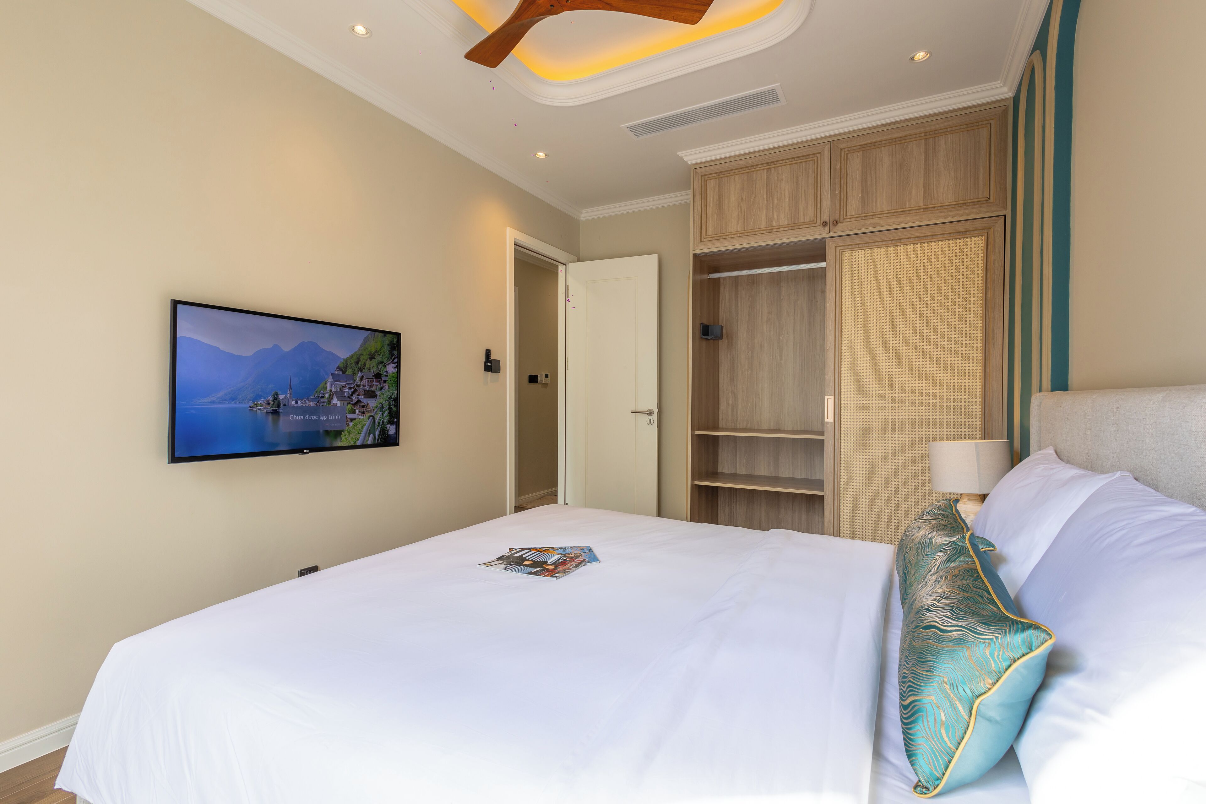 Een hotelkamer met een bed, een aan de muur bevestigde televisie en een kledingkast.