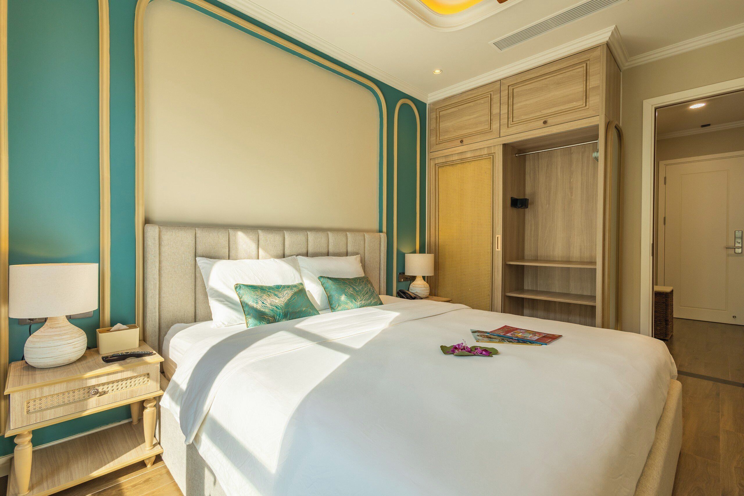 Una cama bien hecha con cabecera, mesitas de noche con lámparas y un armario.