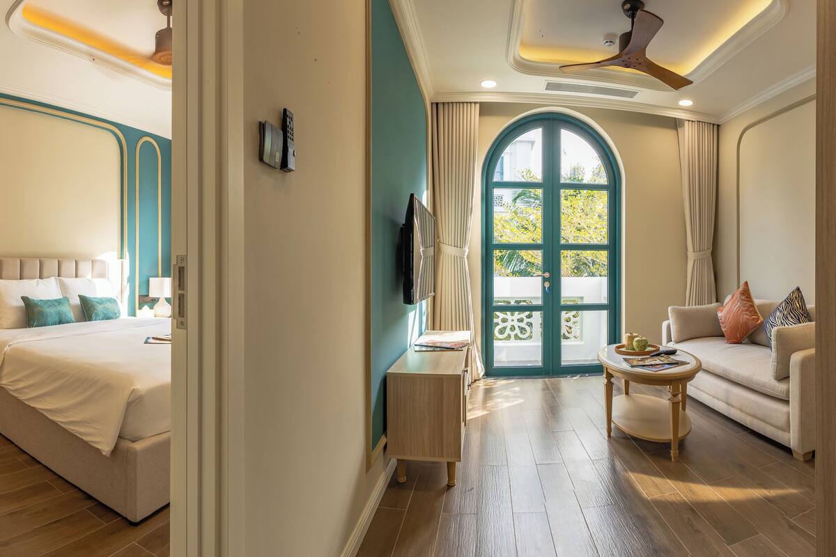 Una habitación de hotel con cama, mesita de noche, lámpara y televisor.