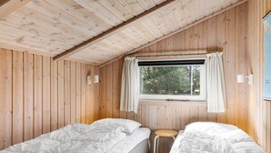 A cabin with wooden walls, two beds, a window with curtains, and a small stool. - "Akka" - 2km from the sea by Interhome (Saltum)