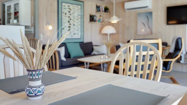 A modern living room with a dining area, featuring a wooden ceiling, a sofa, a coffee table, and a TV mounted on the wall. - "Akka" - 2km from the sea by Interhome (Saltum)