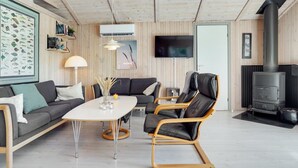 A modern living room with a sofa, two chairs, a dining table, a TV, and a wood-burning stove. - "Akka" - 2km from the sea by Interhome (Saltum)