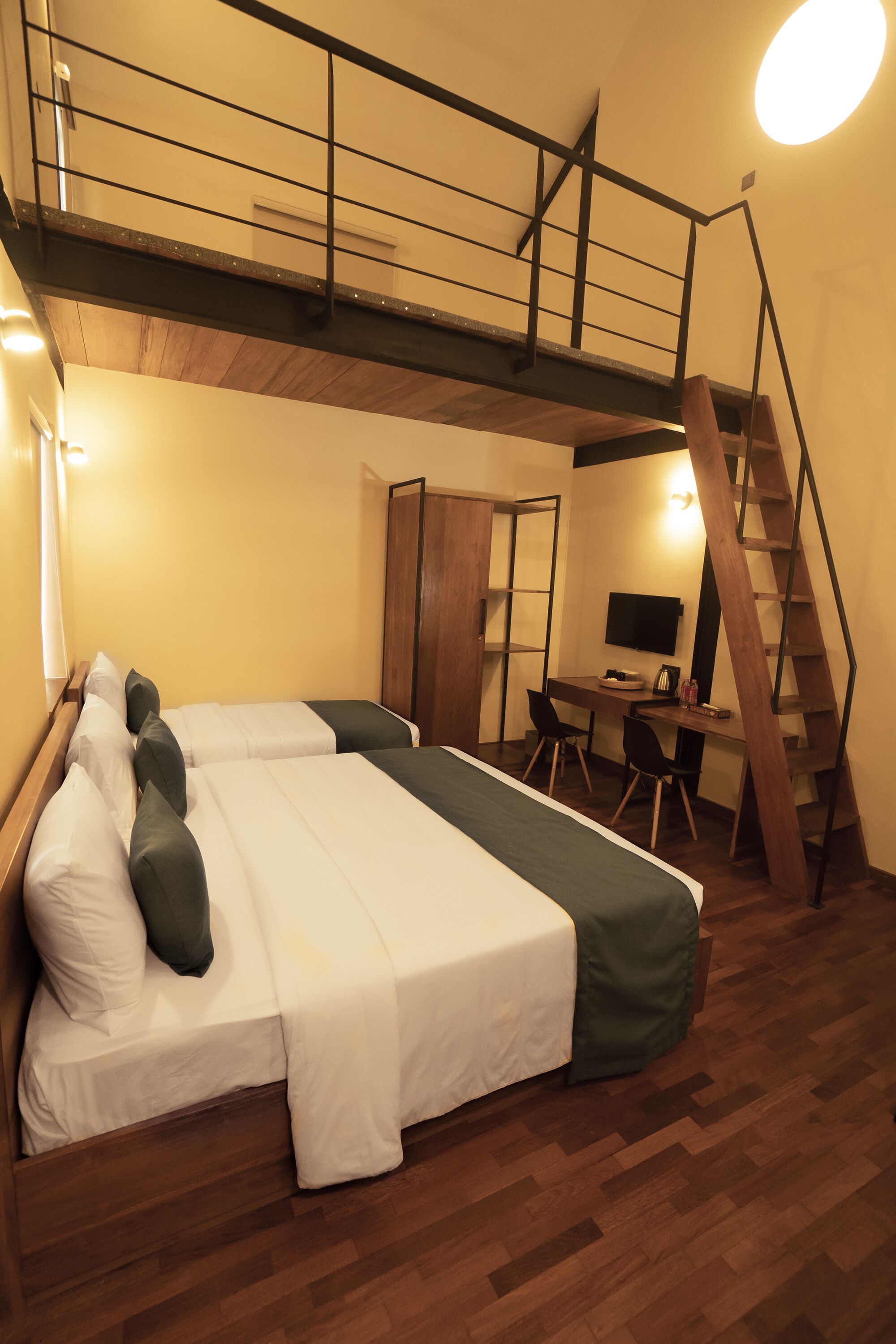 A bedroom with a bed, a desk, and a staircase.