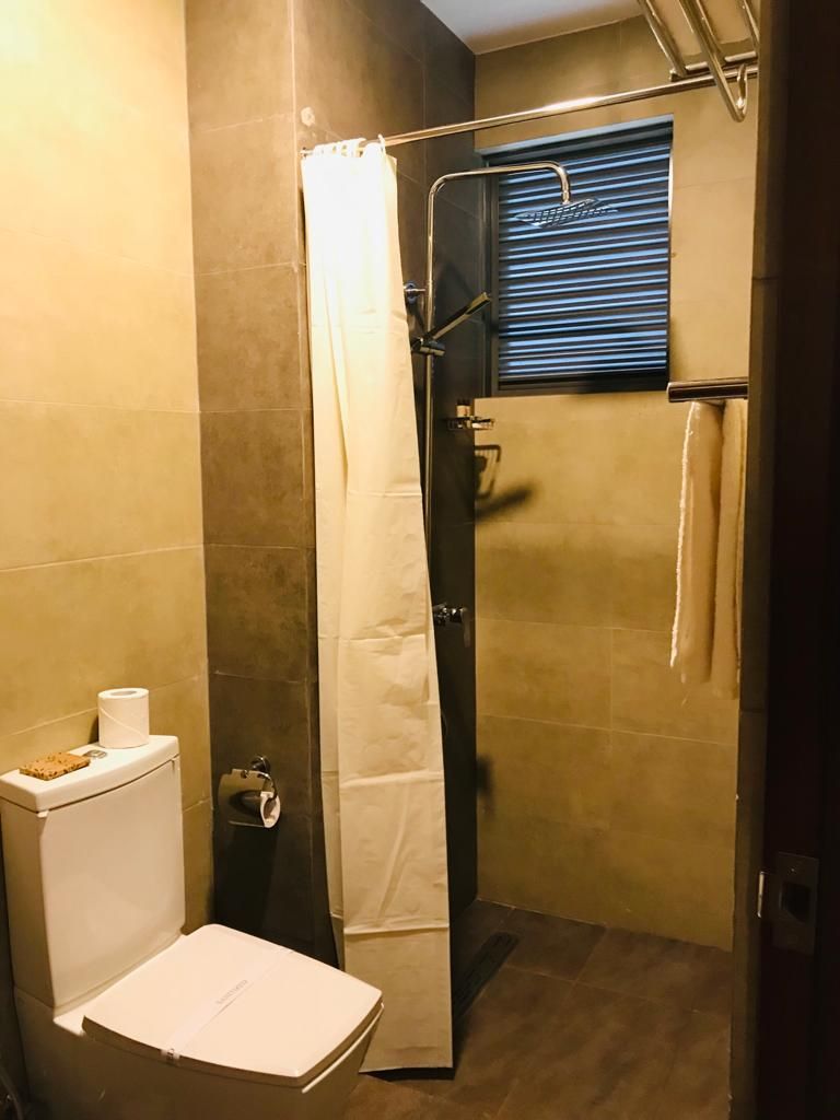Une petite salle de bain comprenant une douche, des toilettes et un porte-serviettes.