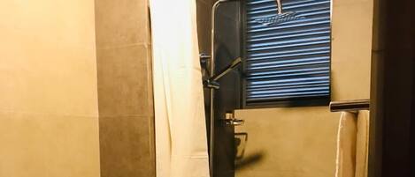 A bathroom with a shower, toilet, and a towel rack.