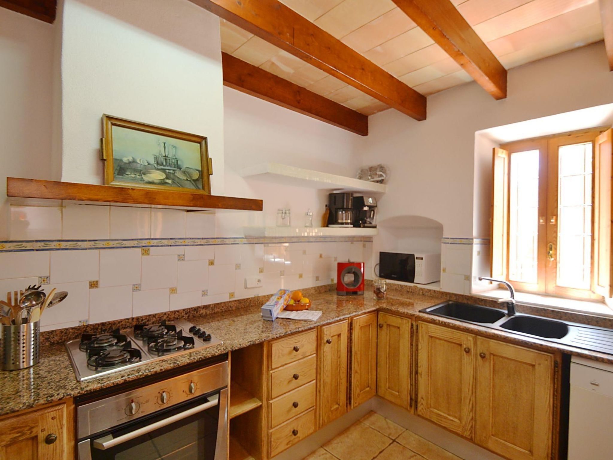 Cuina amb armaris de fusta, fornet a gas, microones i un rentaplat.