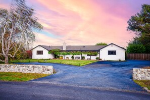 A two-story house with a stone wall driveway, a front yard with a bench, and a tree. - Modern Ranch House-swim, soak, pickleball & walk to wineries (Sonoma)