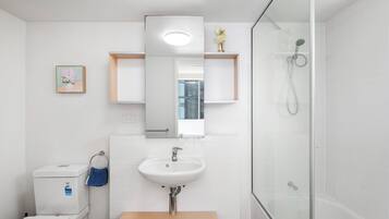 Une salle de bain moderne avec un lavabo blanc, une douche en verre et un meuble-lavabo en bois.