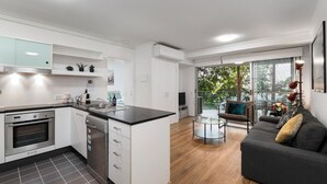 A modern kitchen with white cabinetry, a built-in oven, and a dishwasher. - Allegro Apartments (South Brisbane)