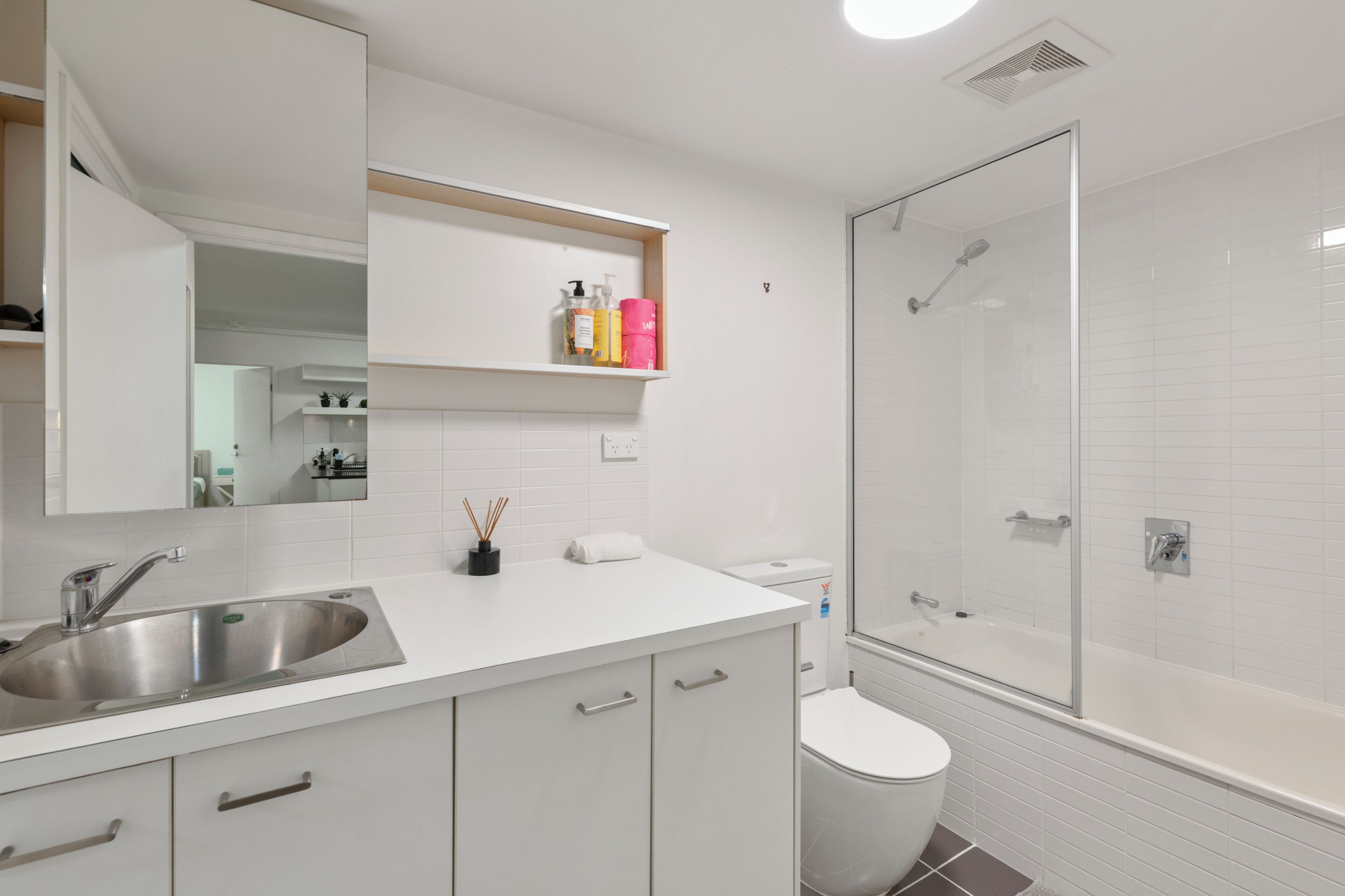 Un baño moderno con lavamanos, inodoro y ducha envuelta en vidrio.
