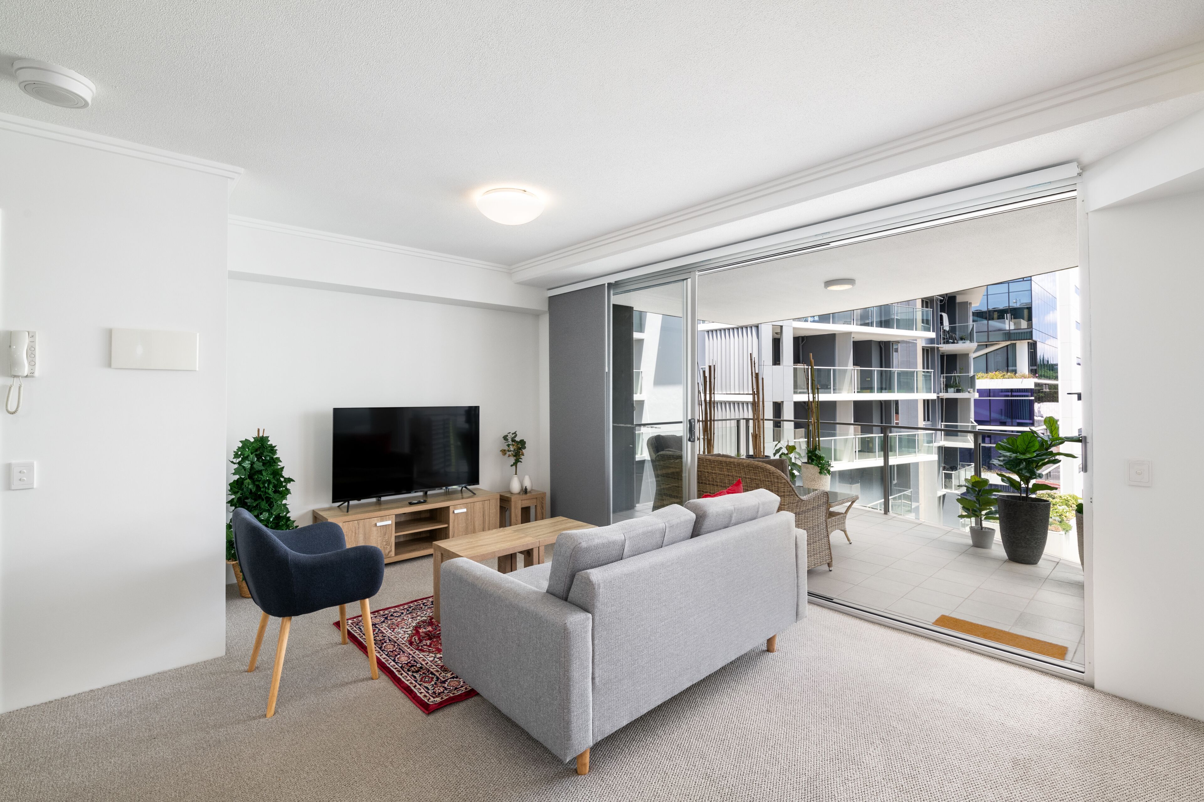 A modern living room with a grey sofa, wooden coffee table, and a flat-screen TV.