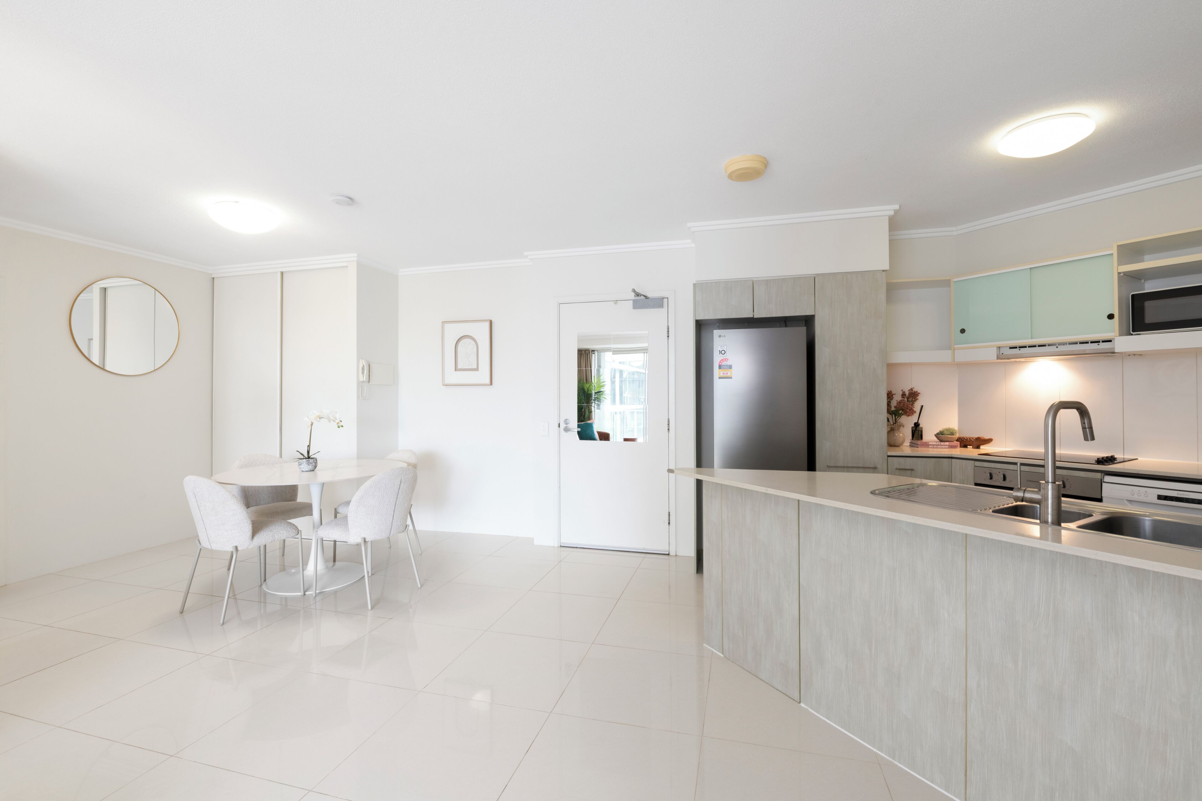 A modern kitchen with a built-in refrigerator, a sink, and a dining area with a table and chairs.