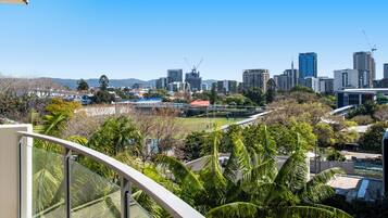 A city skyline with modern buildings, a construction crane, and a park with palm trees.