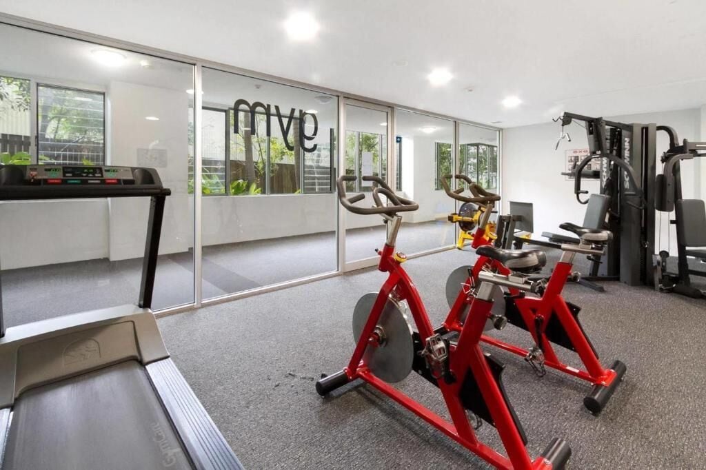 Ein Fitnessstudio mit Cardiogeräten, Kraftmaschinen und einer Spiegelwand.