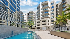 A modern hotel with a swimming pool, multiple balconies, and a clear sky. - Allegro Apartments (South Brisbane)