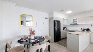 Cozinha moderna com ilha central, área de jantar com mesa redonda e cadeiras, e um espelho grande na parede.