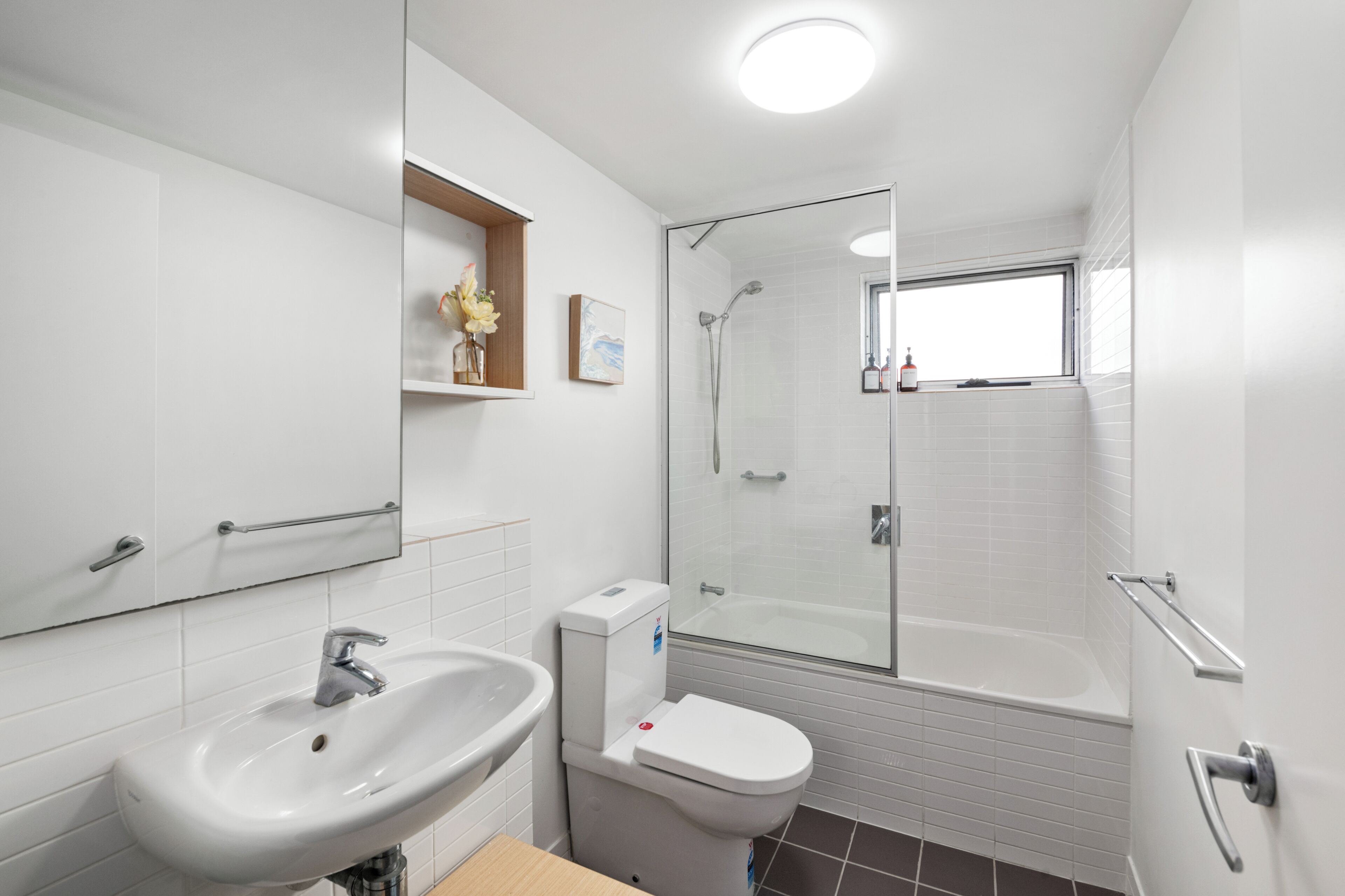 Een moderne badkamer met een witte wastafel, toilet en douchecabine met glazen wanden.