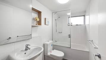 Een moderne badkamer met een witte wastafel, toilet en douchecabine met glazen wanden.