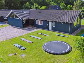 A building with a sloped roof, a small porch, and a trampoline in the yard.