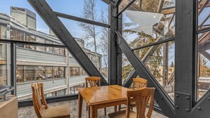 A modern interior with a wooden table and chairs, large windows offering a view of neighboring buildings.
