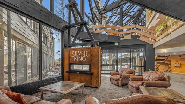 A spacious lobby with leather sofas, a fireplace labeled "SILVER KING," and large windows offering views of the outside.