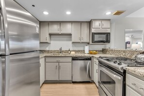 Eine moderne Küche mit Edelstahlgeräten, weißen Schränken und Granit Arbeitsplatten.