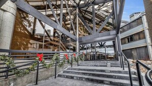 A building under construction with exposed steel framework and a staircase leading to an upper level.