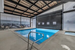 Ein Schwimmbecken mit Metallleiter, Liegestühlen und Blick auf Berge im Hintergrund.