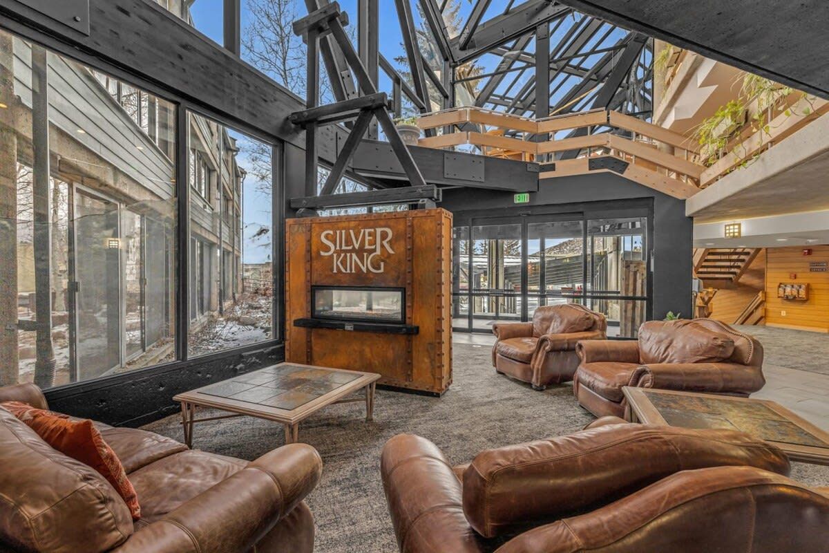 A spacious lobby with leather sofas, a fireplace, and large windows overlooking a snowy landscape.