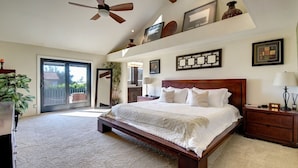 A bedroom with a large bed, a ceiling fan, a sliding glass door, and a wooden nightstand. - Scottsdale Kierland Compound (Scottsdale)