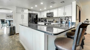 A modern kitchen with white cabinets, stainless steel appliances, and a granite island. - Scottsdale Kierland Compound (Scottsdale)