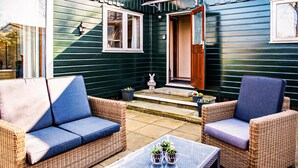 A patio area with wicker furniture, a glass table, and potted plants. - Nice (sta)caravan in Reutum with WiFi (Reutum)