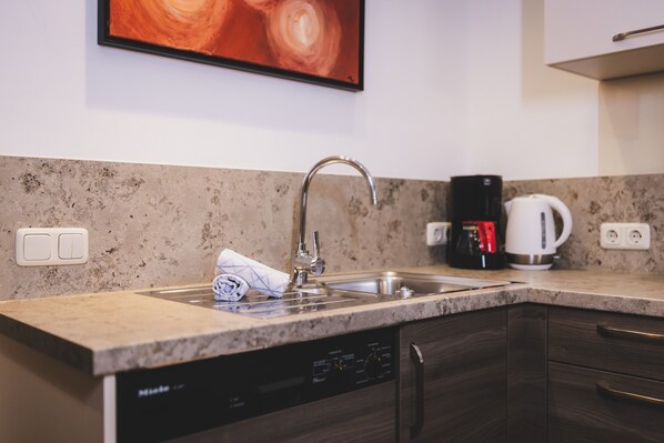 A kitchen with a dishwasher, a coffee maker, and a sink. - Apartment 'Nr 12 Haus Voglreiter' with Mountain View, Shared Garden and Wi-Fi (Kaprun)
