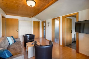 Un salon moderne avec un canapé, un fauteuil en cuir, une table basse et un téléviseur.