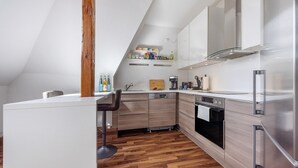 A modern kitchen with a wooden floor, white cabinets, stainless steel appliances, and a bar stool.