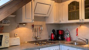 A kitchen with white cabinetry, a built-in oven, a stove, and a sink.