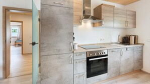 A modern kitchen with a built-in oven, stainless steel appliances, and wooden cabinets.