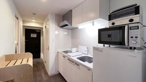 A compact kitchen with white cabinetry, a microwave, a built-in oven, and a sink.