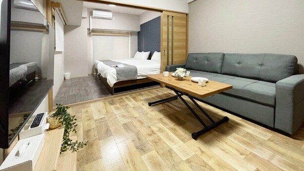 Une chambre d’hôtel de taille réduite, comprenant un lit, un canapé, une télévision et une table en bois.