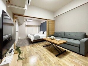 Une chambre d’hôtel de taille réduite, comprenant un lit, un canapé, une télévision et une table en bois.