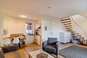 A modern apartment with a kitchen, dining area, living room, and a spiral staircase.