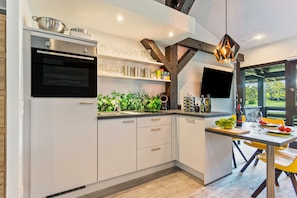 A modern kitchen with built-in appliances, a dining area with yellow chairs, and a large window.