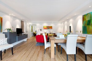 A modern living room with a dining area, a TV, and artwork on the walls.