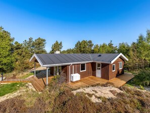 A modern wooden cabin with a sloped roof, large windows, and a deck.