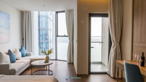 Quarto de hotel moderno com varanda, um sofá, uma pequena mesa e um espaço de refeições.