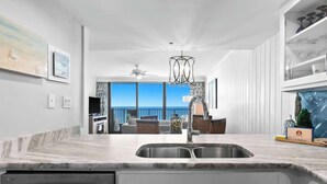Une cuisine moderne dotée d’un grand îlot central, d’un four encastré et donnant sur un balcon.