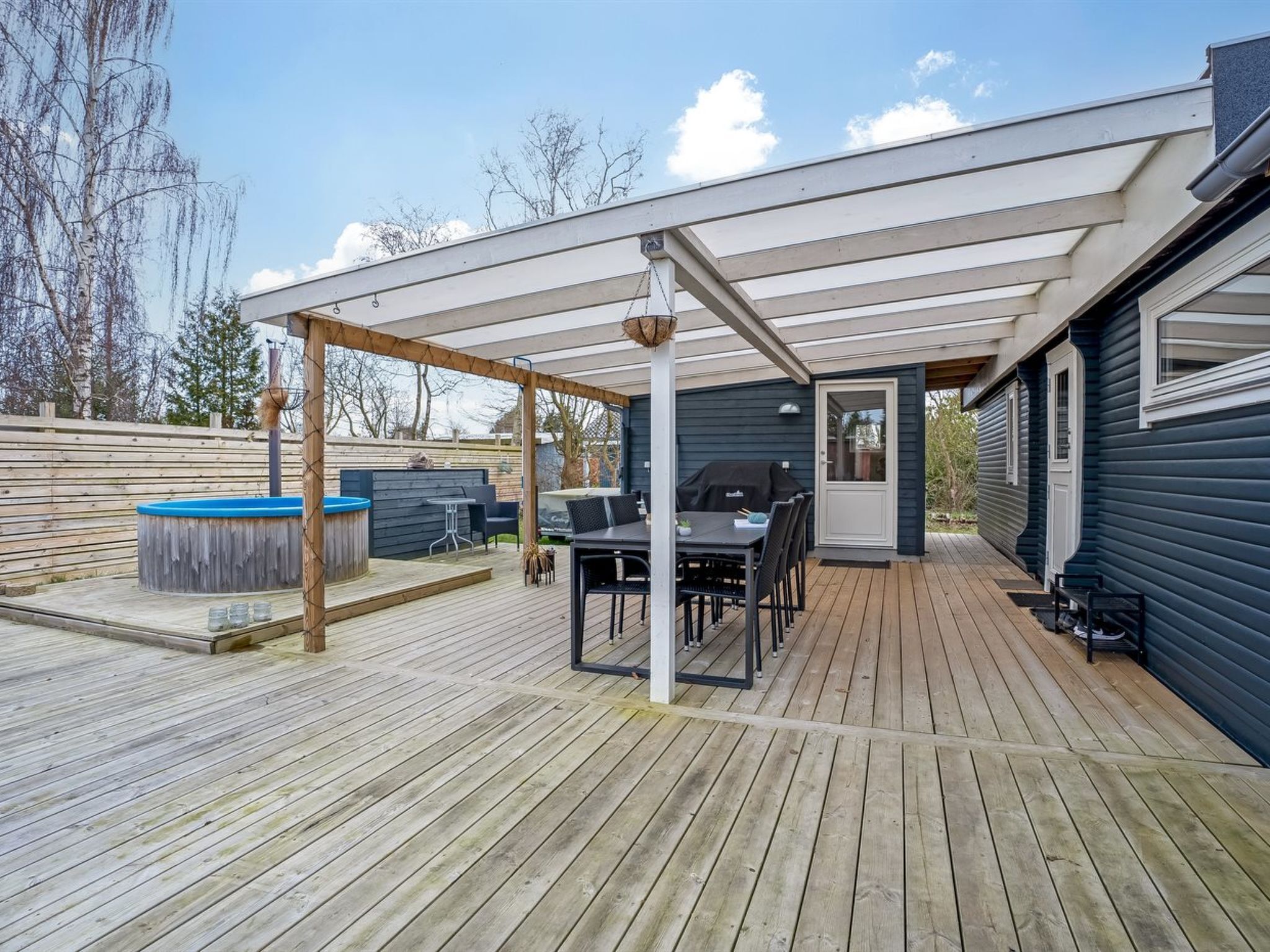 A covered patio with a grill, hot tub, and outdoor seating area.