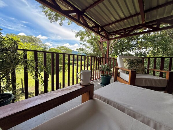 A covered outdoor seating area with a view of a green landscape.